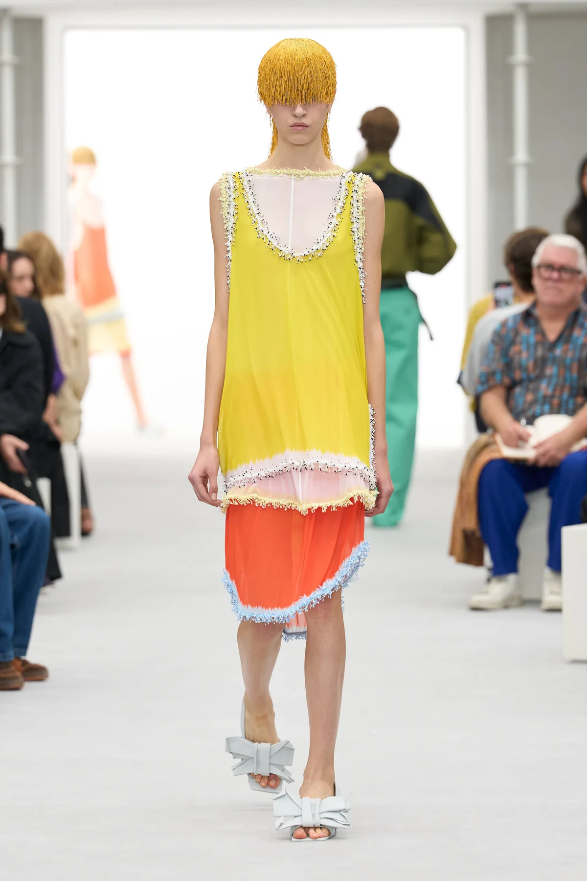 Model in a yellow and tangerine color-bleed slip dress with fringed trim at the Loewe Spring Summer 2027 show