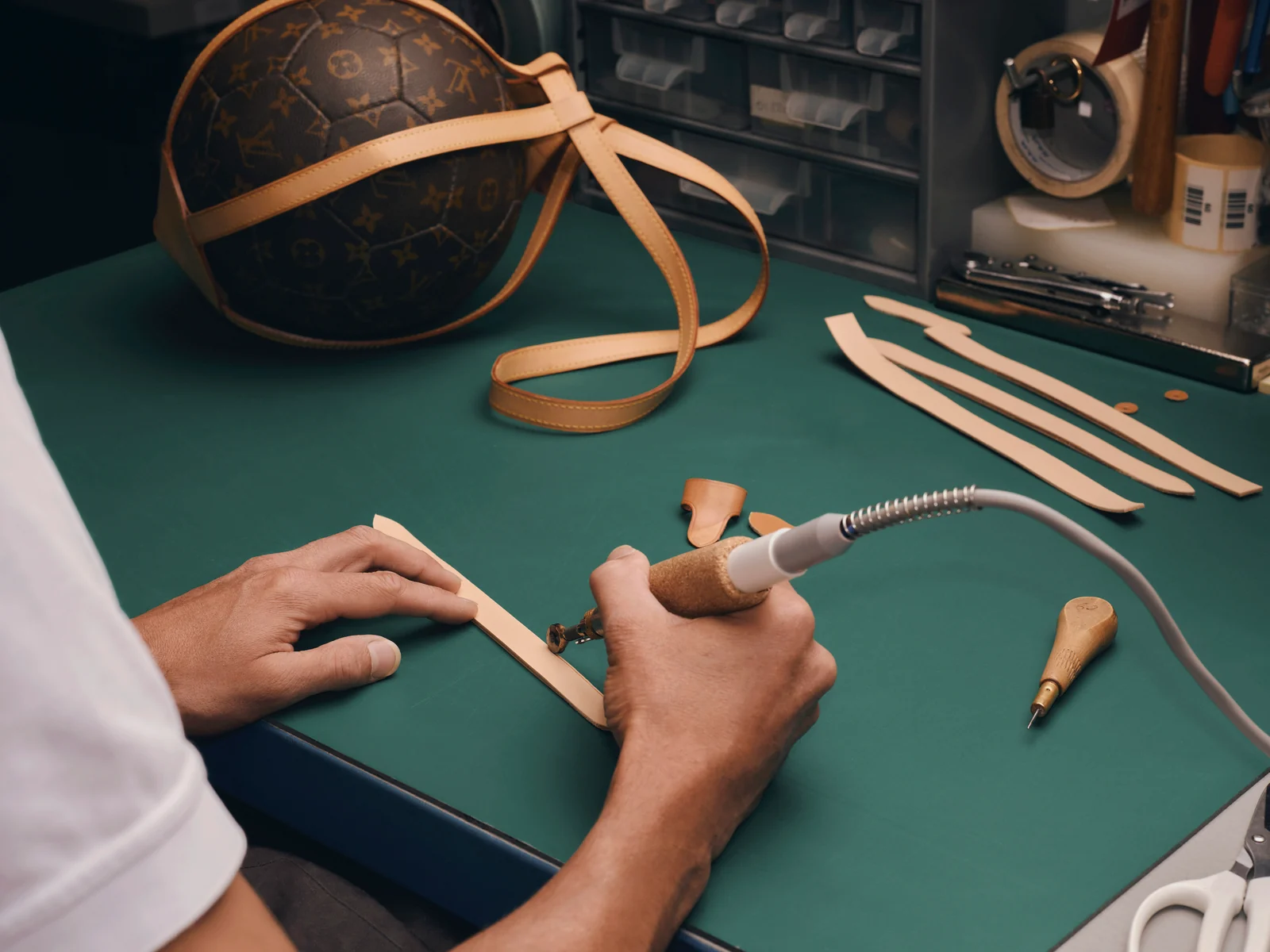 Louis Vuitton Care & Repair: artisan restitching the leather straps of a Monogram ball bag
