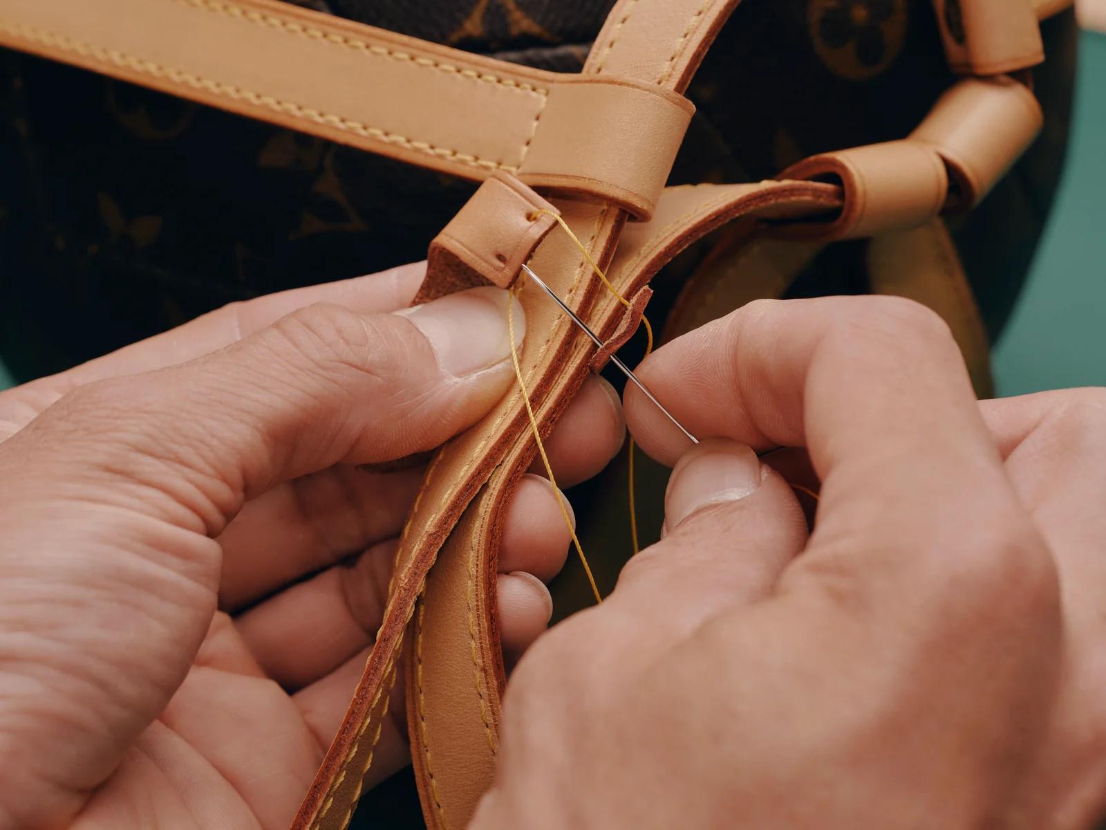 Louis Vuitton Care & Repair: artisan hands working a leather strap