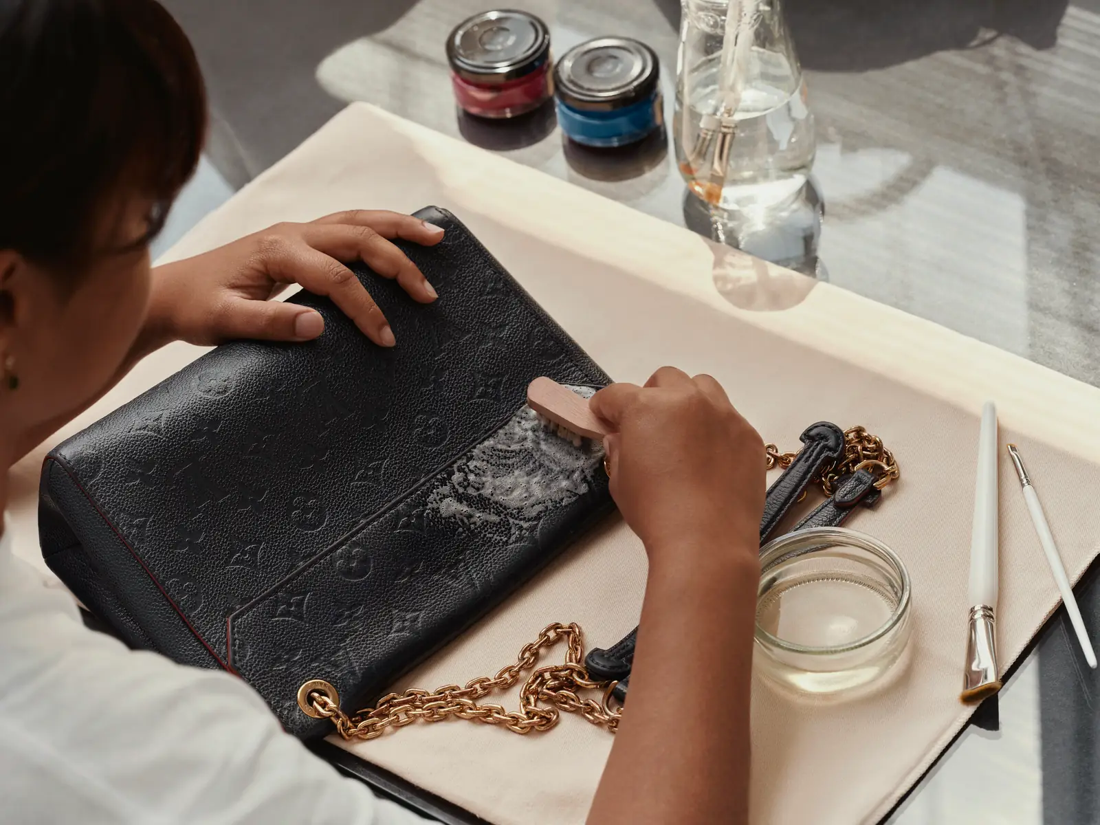 Louis Vuitton Care & Repair: artisan recoloring a black leather bag