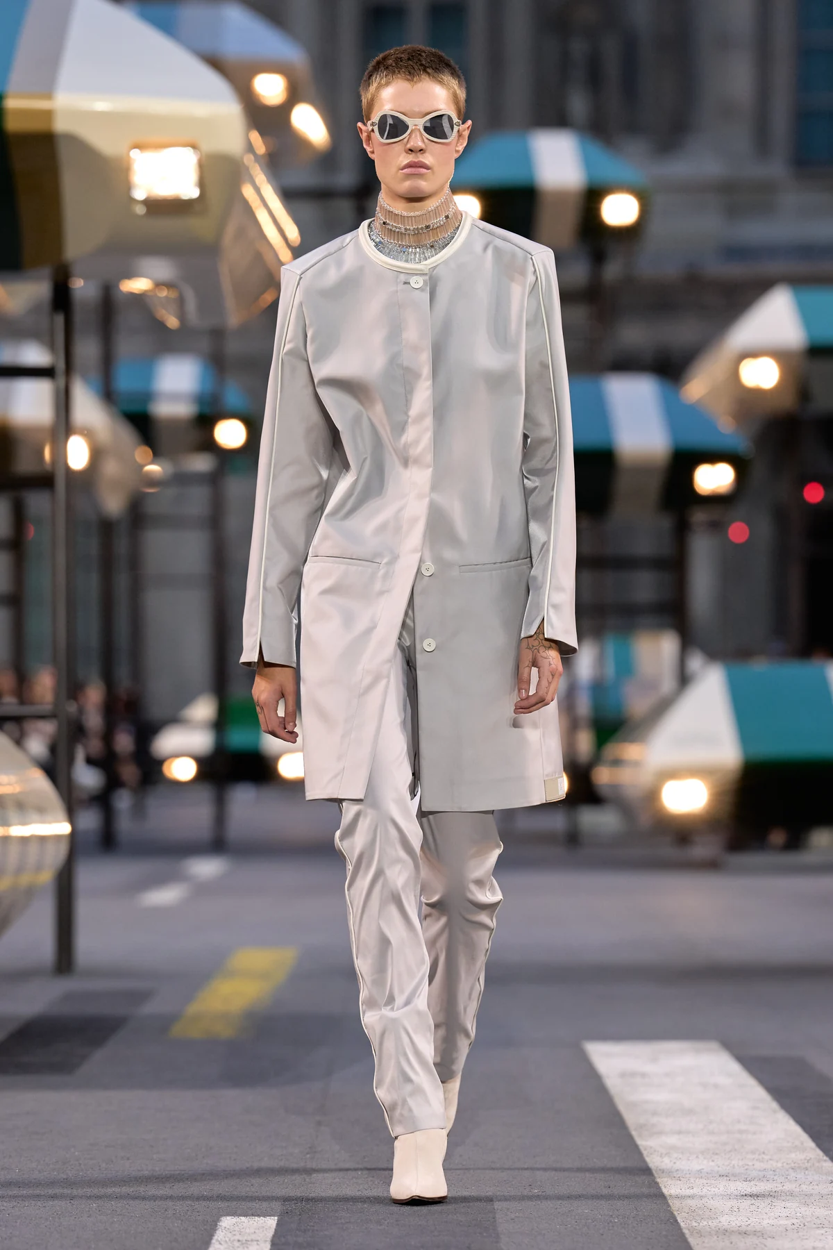 Look 8, a silvery gray collarless longline jacket and slim trousers with goggle-like glasses, from Louis Vuitton Spring Summer 2027