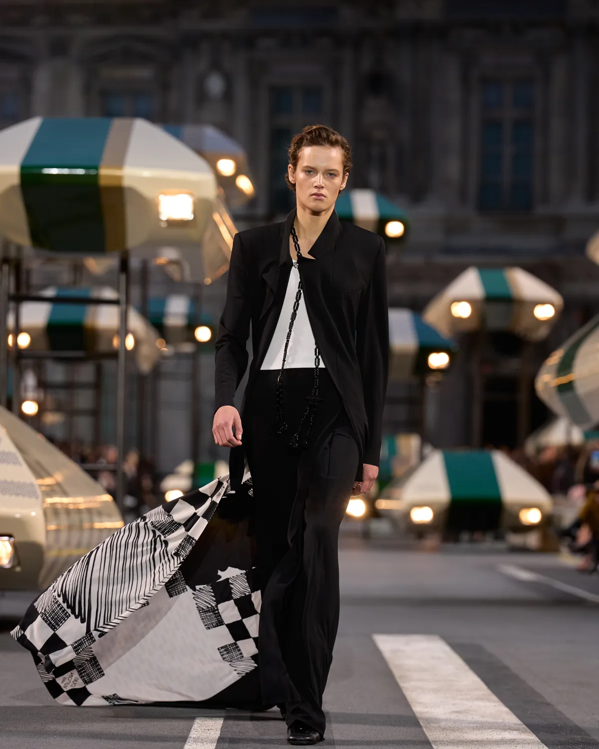 Louis Vuitton Spring/Summer 2027 Look 48, a black suit trailing a checked carré scarf, at Paris Fashion Week