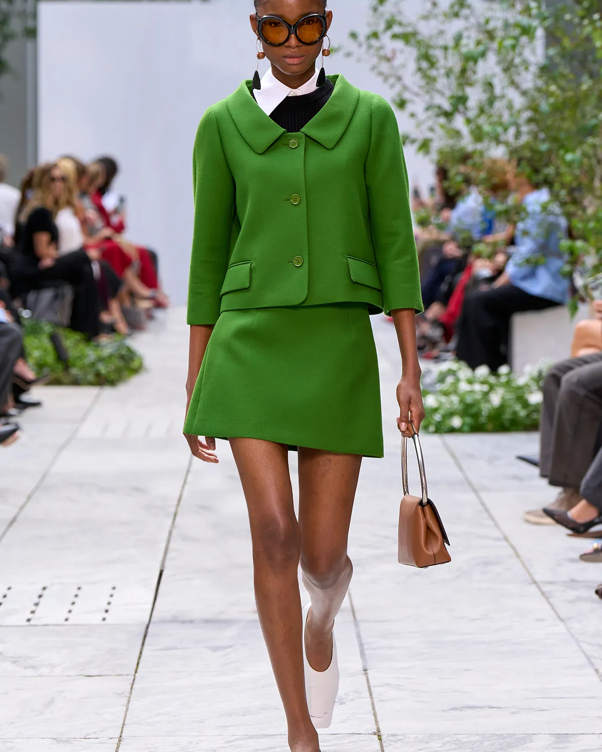 Michael Kors Collection Spring 2027 Look 9, a bright green micro skirt suit, at New York Fashion Week