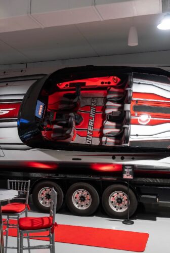 Cockpit and helm seats of the red Outerlimits SC37 catamaran, with an SC37 sign on display at the Fort Lauderdale dealership