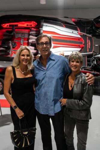 Guests gathered at the stern of the red Outerlimits SC37 catamaran inside the Fort Lauderdale dealership