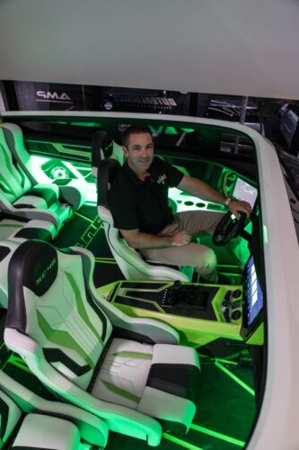A CMC Boat Group host at the helm of the green-and-white Outerlimits SC46 catamaran during the Fort Lauderdale dealership celebration
