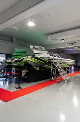 The green-and-white Outerlimits SC46 catamaran displayed on a red carpet at the Outerlimits Fort Lauderdale dealership