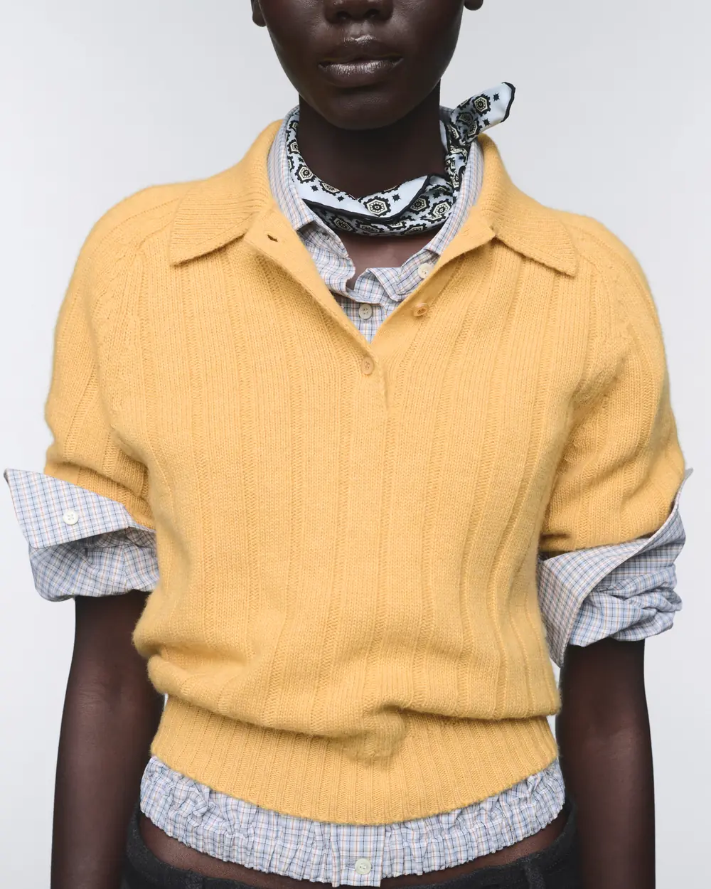 Model wearing a yellow short-sleeved Prada Re-Cashmere polo sweater over a checked shirt