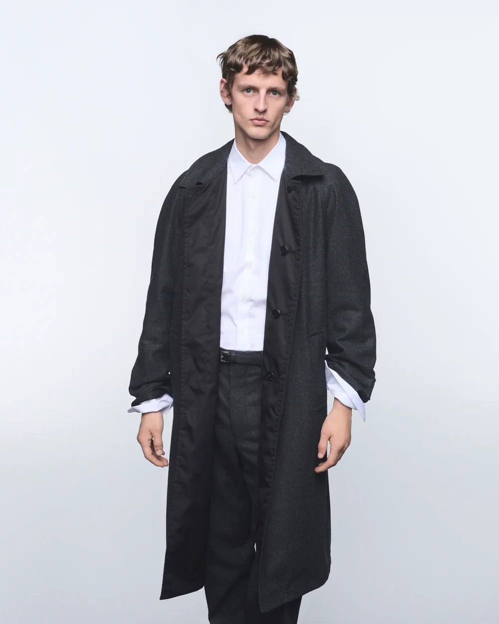 Model in a long black Prada Re-Wool coat over a white shirt