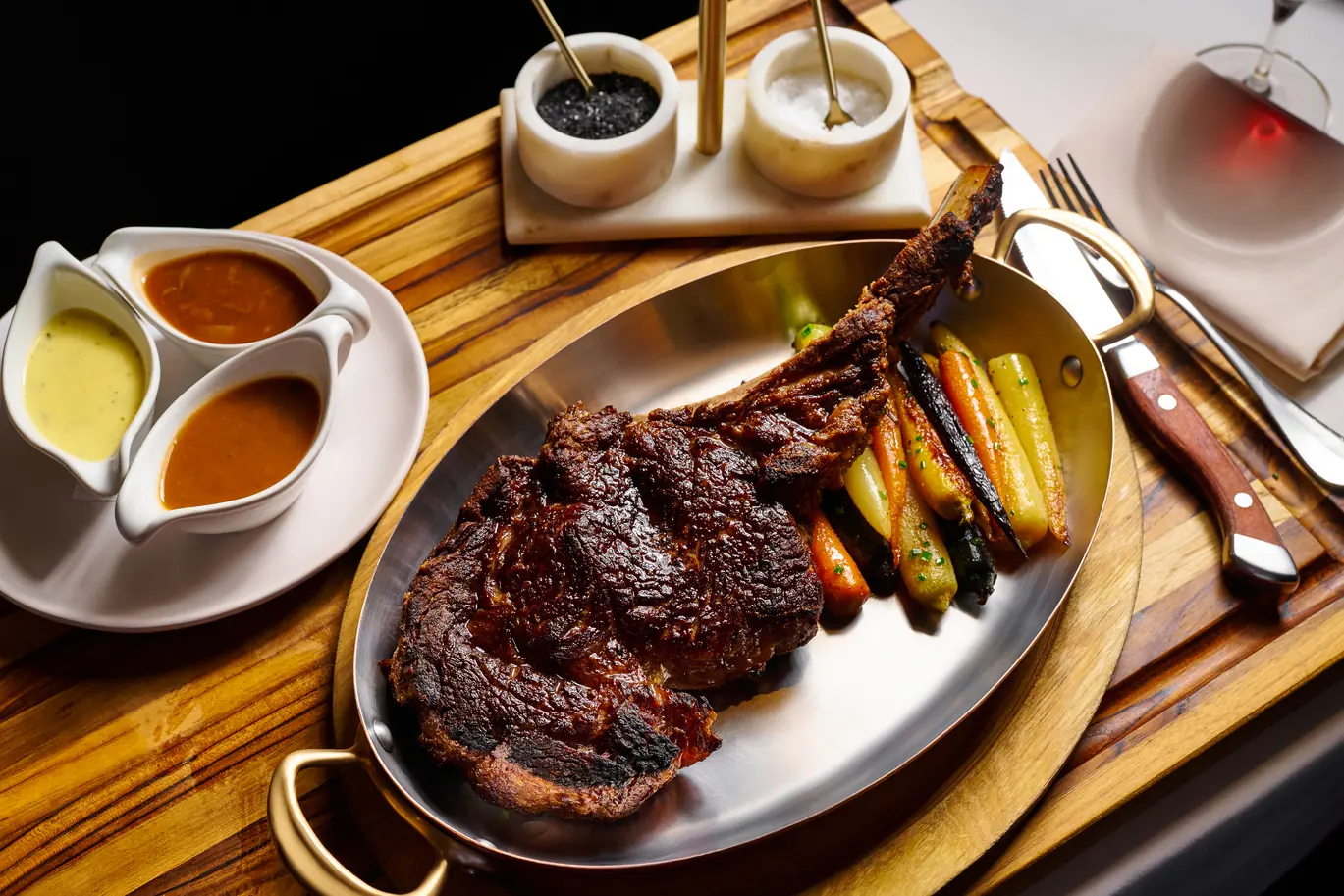 Reserve Cut New York steakhouse dry-aged bone-in steak with sauces and roasted carrots