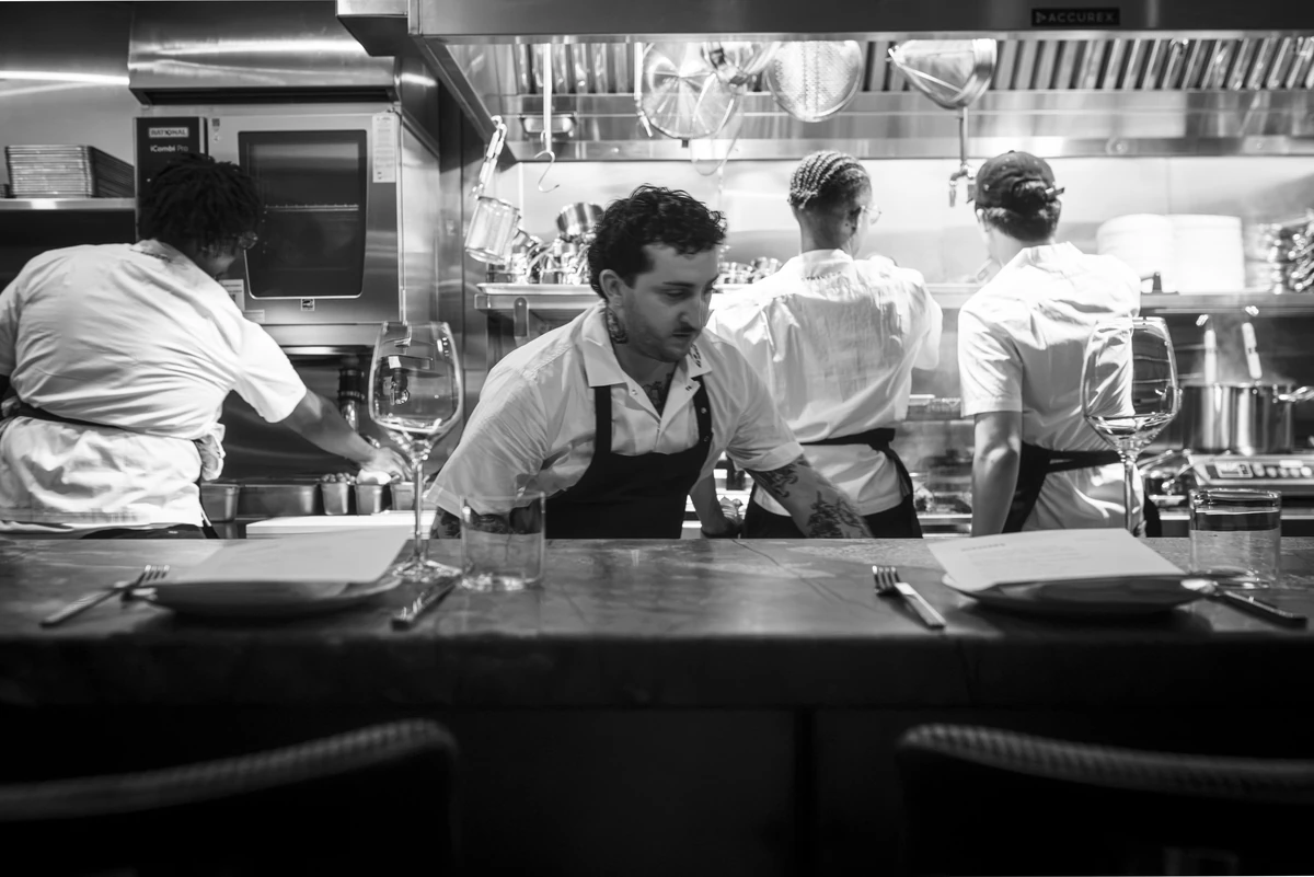 Black-and-white view of the kitchen team in whites and aprons working behind the counter at Straker’s Soho