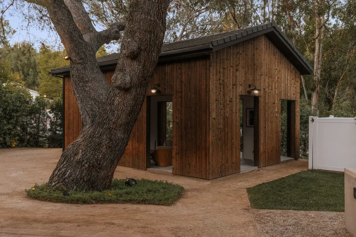 Three Planes Hidden Hills exterior with dark wood siding beneath a mature oak