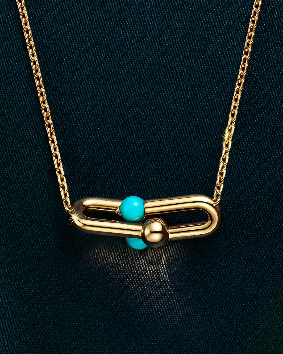 Tiffany HardWear Medium Link Pendant in 18k yellow gold with turquoise on a chain against dark teal satin