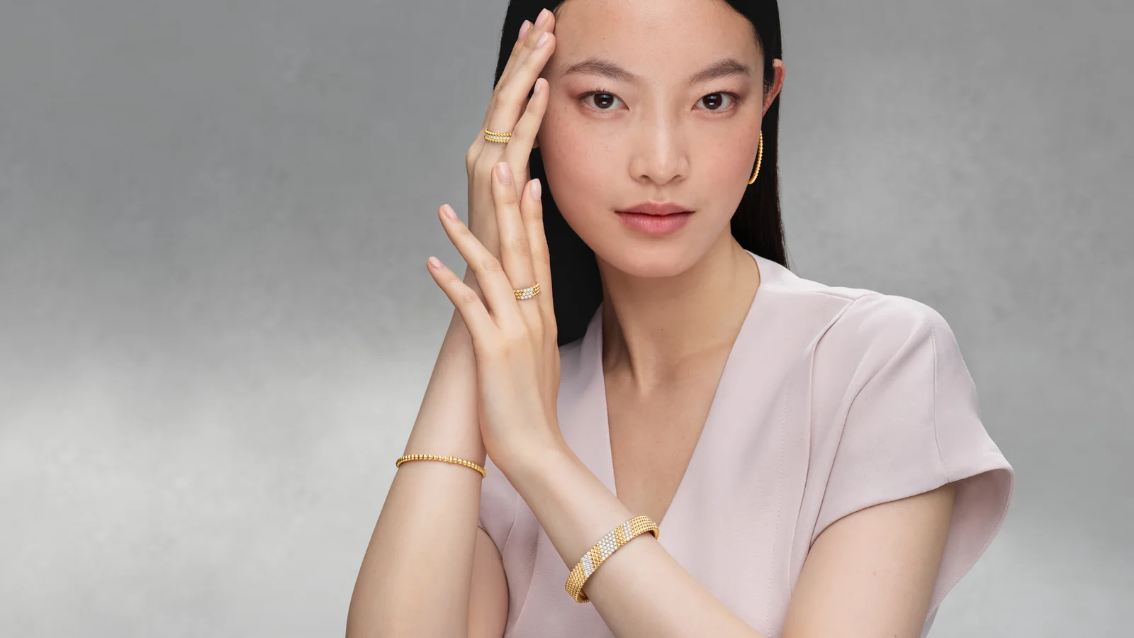 Model wearing Perlée gold hoop earrings, rings and bangles, Van Cleef Perlée Las Vegas campaign image