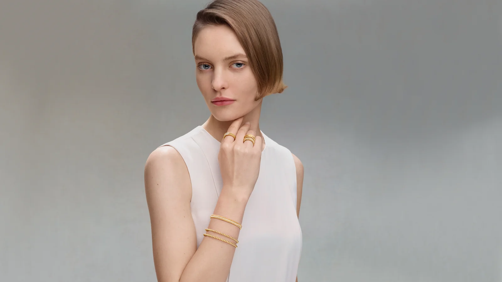 Model in a white top wearing Perlée gold rings and stacked bangles, Van Cleef Perlée Las Vegas campaign image